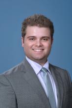 man in light grey suit with short hair smiling