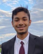 man in a suit and deep red tie smiling