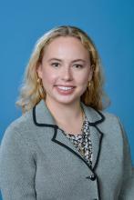 woman with blonde curly hair and grey blazer smiling