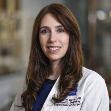 woman with brown hair in a white doctor coat smiling