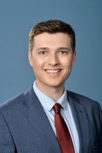 man in grey-blue blazer smiling