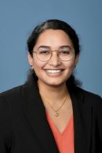 woman with glasses and hair pulled back smiling