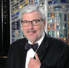 man with glasses and suit with bowtie smiling
