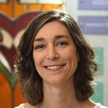 woman with short curled brown hair smiling