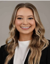 woman with long curled blonde hair and black blazer smiling