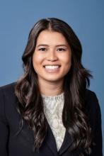 woman with long dark brown hair and dark blazer smiling