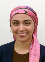 woman with pink headwrap and small hoop earrings smiling