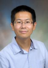 man with light blue button down and glasses smiling