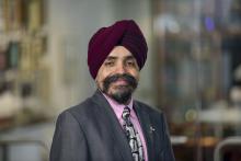 man with a grey blazer and pink shirt with a beard smiling