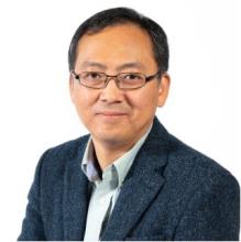 man with grey blazer and glasses on smiling