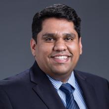 man with dark hair and blazer on smiling