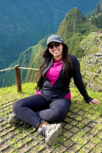 woman sitting cross-legged with mountains behind her