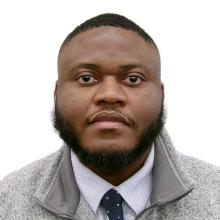 man with dark hair in a buzz cut smiling