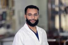 headshot of man with dark hair, beard and glasses on