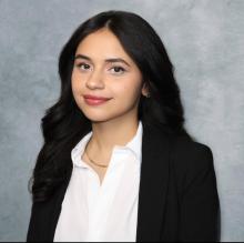 woman in white top with long dark hair smiling lightly