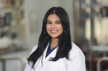 woman with long dark hair in a middle part smiling