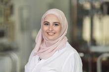 woman with a light pink head wrap on smiling