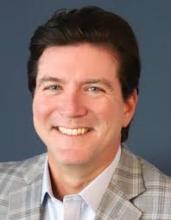 Man smiling in front of grey background