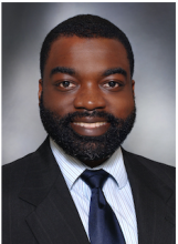 Male smiling with facial hair, wearing suit and tie