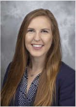 Female with long red hair, smiling, black blazer