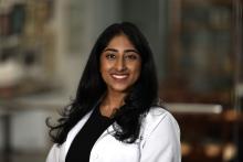 woman with a black shirt on under her doctor coat smiling