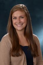 woman with dark blonde hair and a beige sweater on smiling