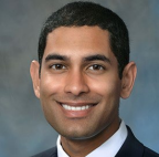 Male smiling with short dark hair. Wearing suit and tie 
