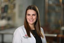 woman in a white doctor coat with brown hair smiling