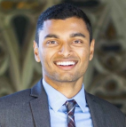 Male with short dark hair wearing suit and tie