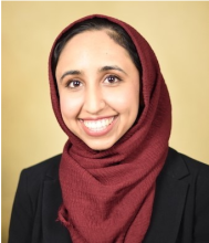 Female smiling with maroon scarf on head, with black shirt