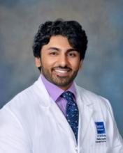 man with dark curly hair smiling