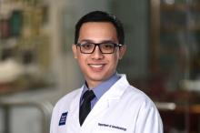 man with dark hair and black glasses on smiling