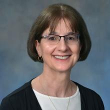 woman with short brown hair and glasses on smiling