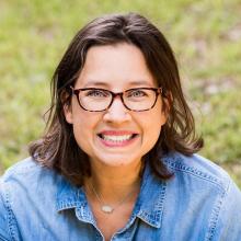 woman in a blue jean top with short brown hair smiling