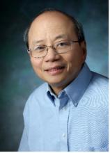 man with small square glasses smiling