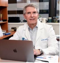 male doctor sitting at a laptop smiling