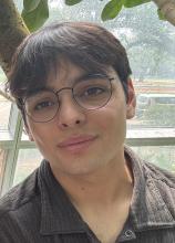 man smiling in front of a curved window