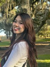 woman smiling outside in front of a tree