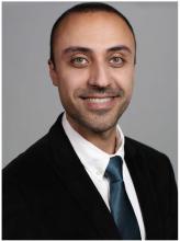 man with short hair and light eyes smiling