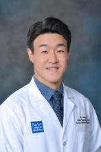 man with dark, side parted hair smiling