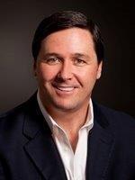 man with brown hair in a suit smiling