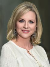 woman in a white top with shoulder length blonde hair smiling