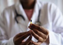 Photo of a doctor holding a syringe to vaccinate a patient. 