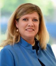 woman with blonde hair in a blue top smiling