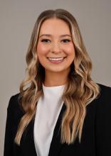 woman with long blonde hair in a black blazer smiling