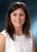 woman with brown hair and a white shirt on smiling