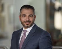 man in a dark gray suit smiling lightly