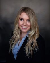 female with long blonde hair, wearing black blazer and blue shirt