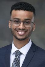 man with short curly hair and glasses on smiling
