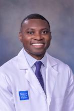 man in a doctor coat with a buzz cut smiling